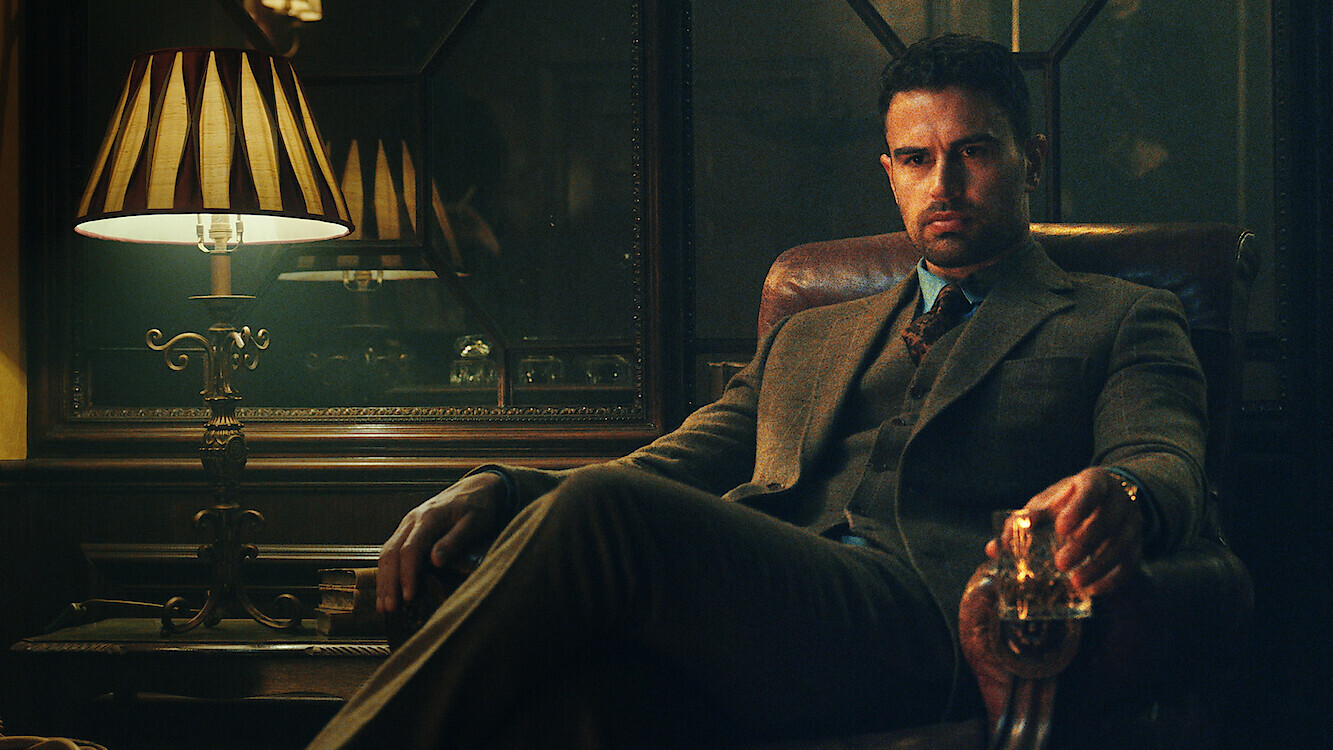 Official Netflix Tudum still for The Gentlemen Season 2. Theo James as Eddie Horniman in the chair with a glass. Photo by Christopher Raphael / Netflix.